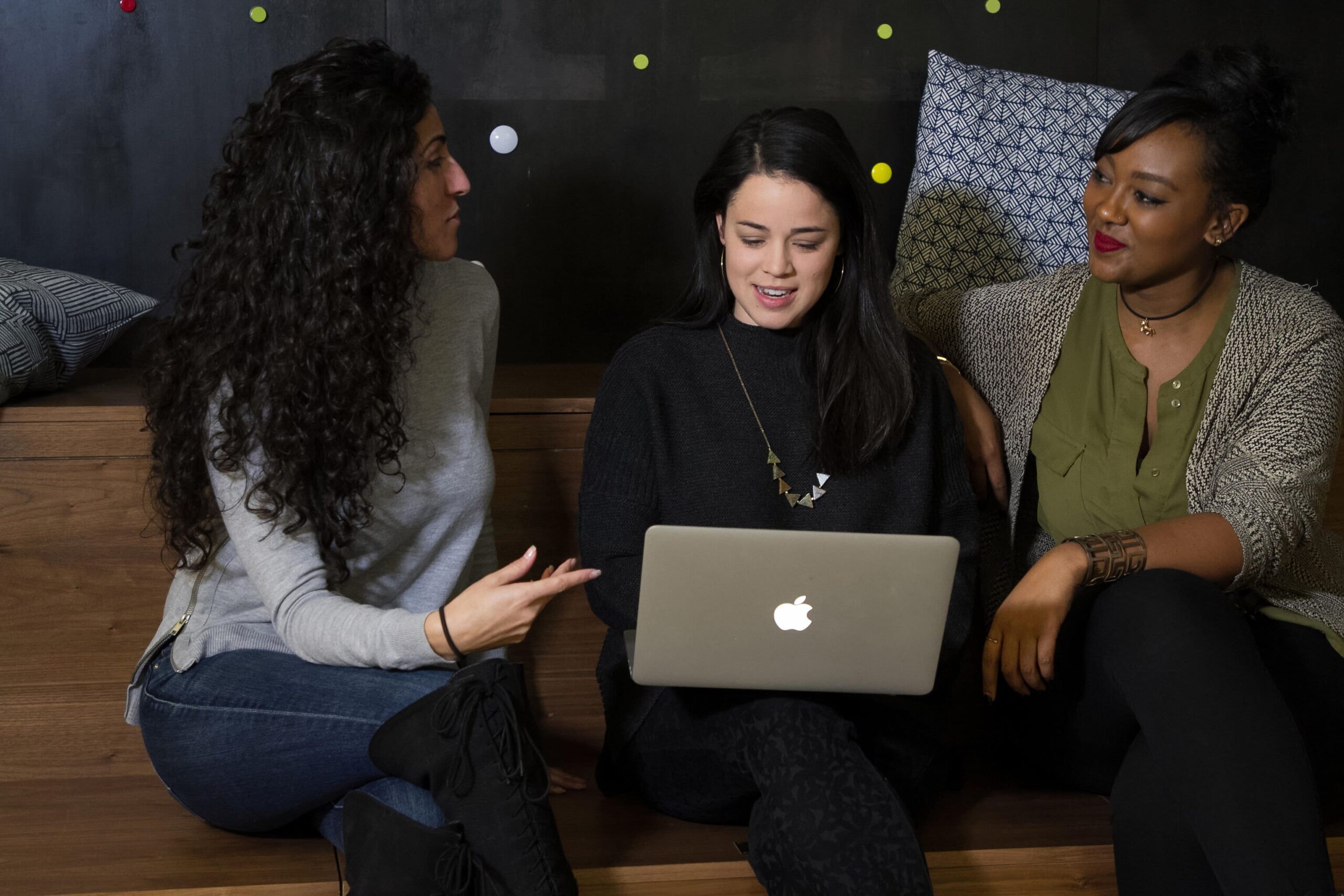 three-women-discussing-macbook-laptop_2022-Sept-Blog_banner